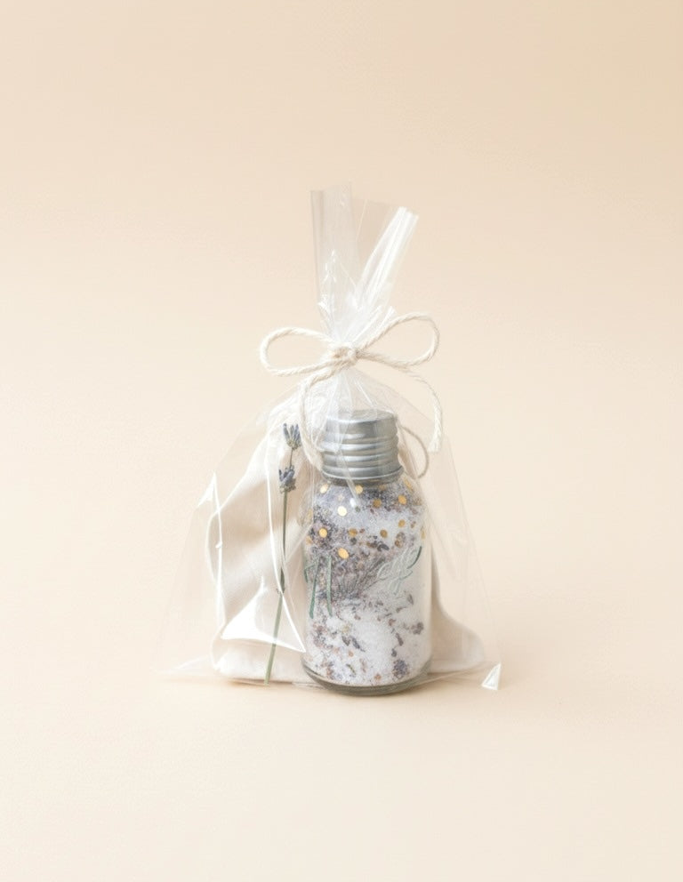 Decorative bottle with silver cap and floral design in a clear bag on a beige background