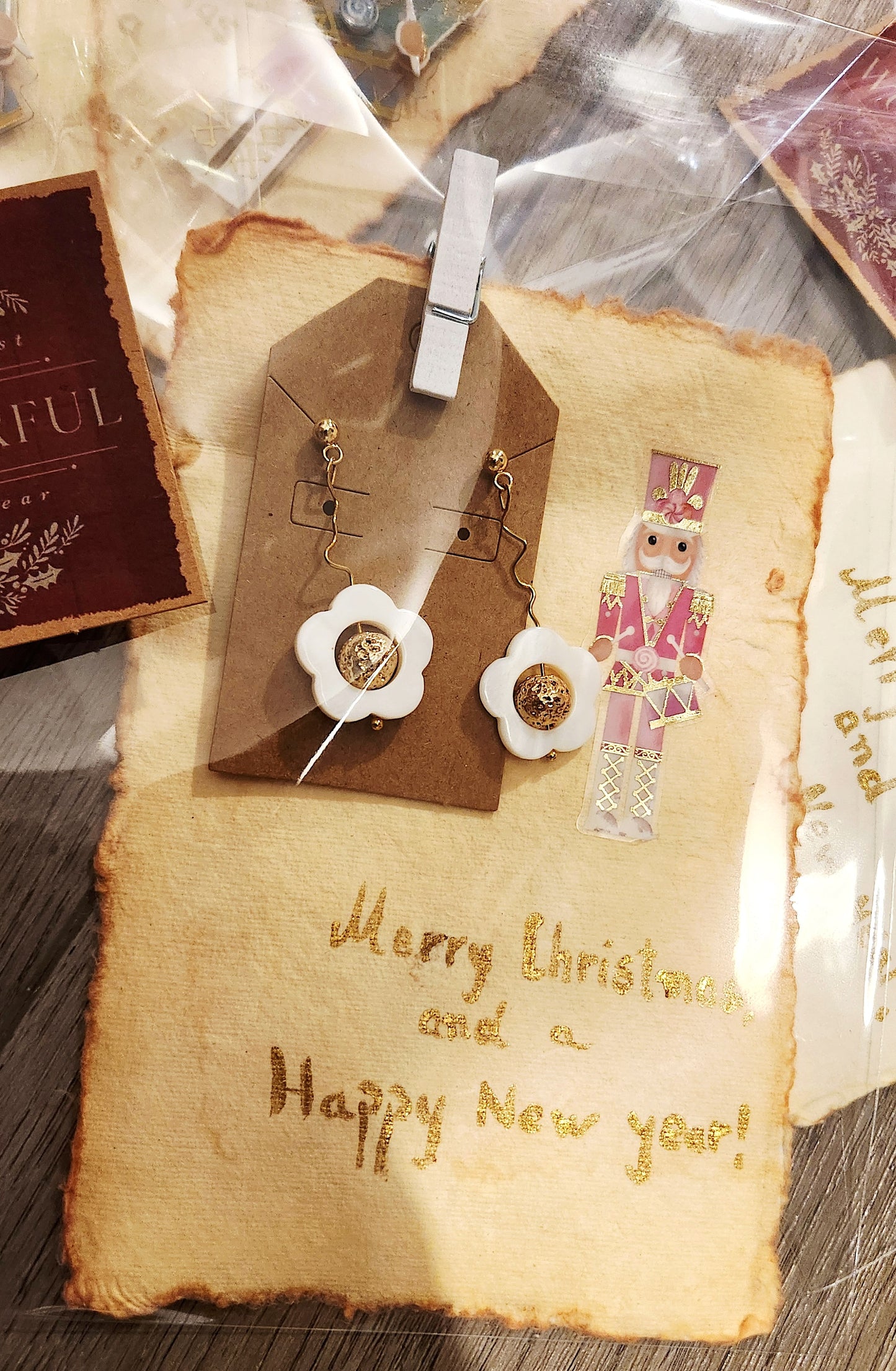 Vintage-style card with 'Merry Christmas and a Happy New Year!' text, decorative tags, and a nutcracker figure. 18 k gold plated  floral earrings