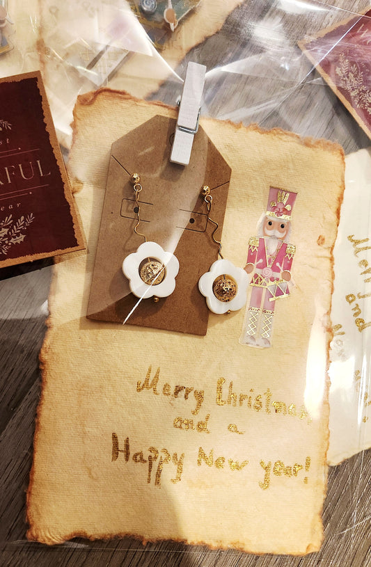 Vintage-style card with 'Merry Christmas and a Happy New Year!' text, decorative tags, and a nutcracker figure. 18 k gold plated  floral earrings